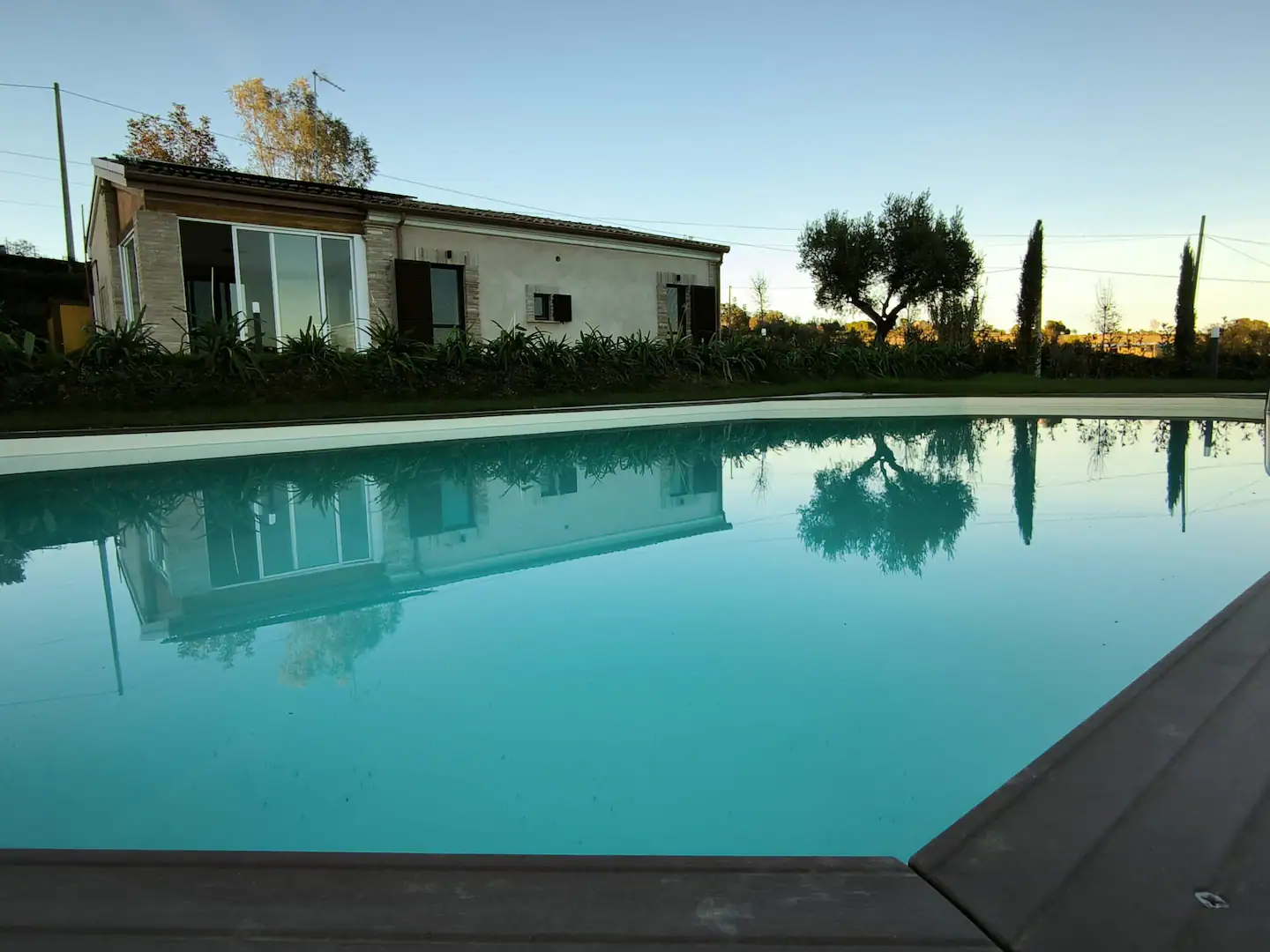 La facciata della villa riflessa nell'acqua turchese della piscina