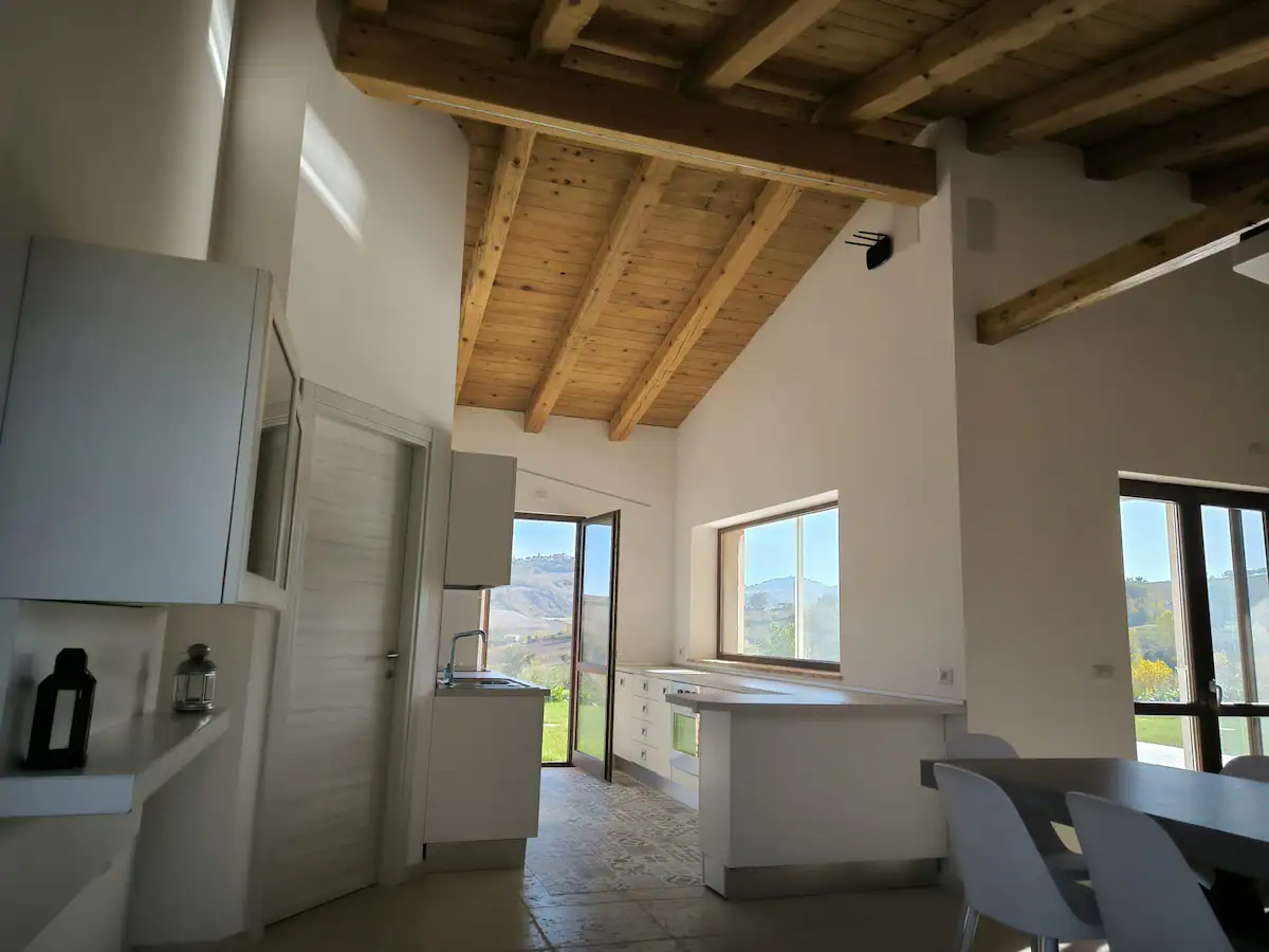 Cucina open space con soffitto in legno e vista sulla campagna