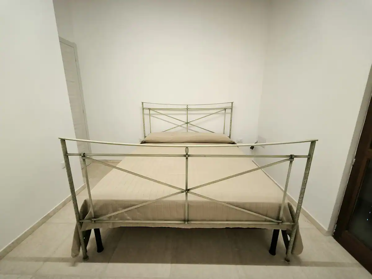 Camera matrimoniale luminosa con letto in ferro dal disegno geometrico