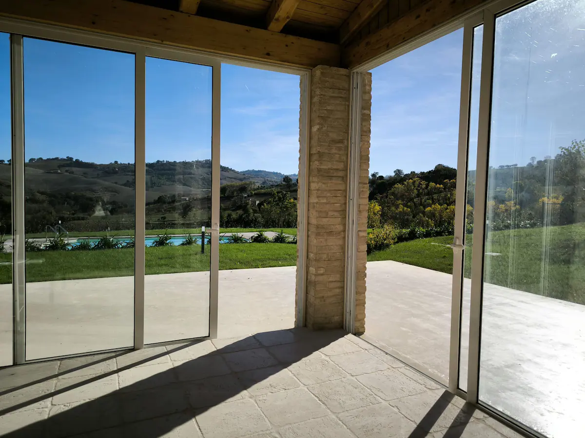 Veranda vetrata aperta sulla piscina e sulle colline